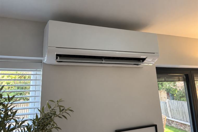 Wall-mounted air conditioning unit installed in a living space beside garden doors