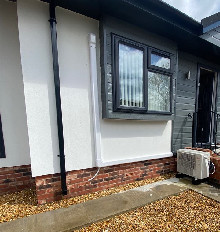 Air conditioning outdoor unit beside a park home on Mossways Park, Wilmslow